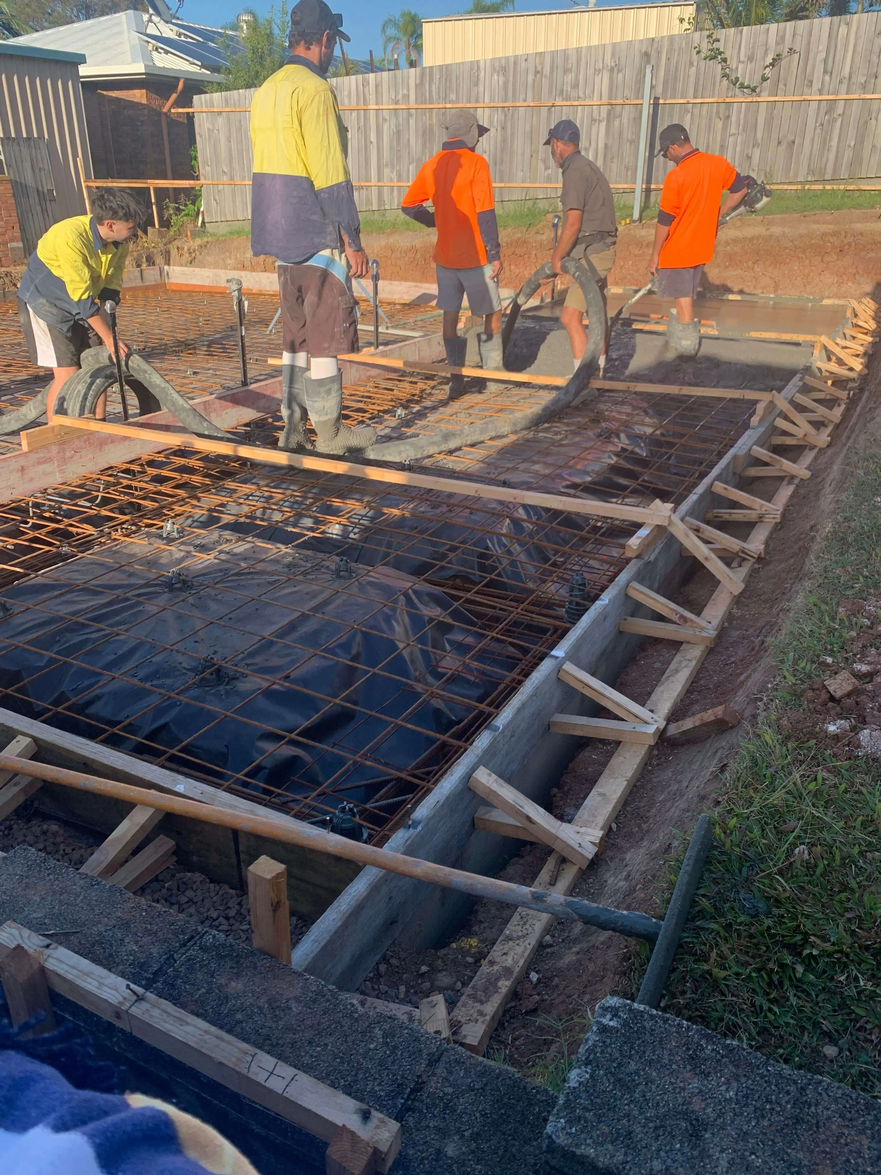 Crew placing and screeding concrete for a house extension slab