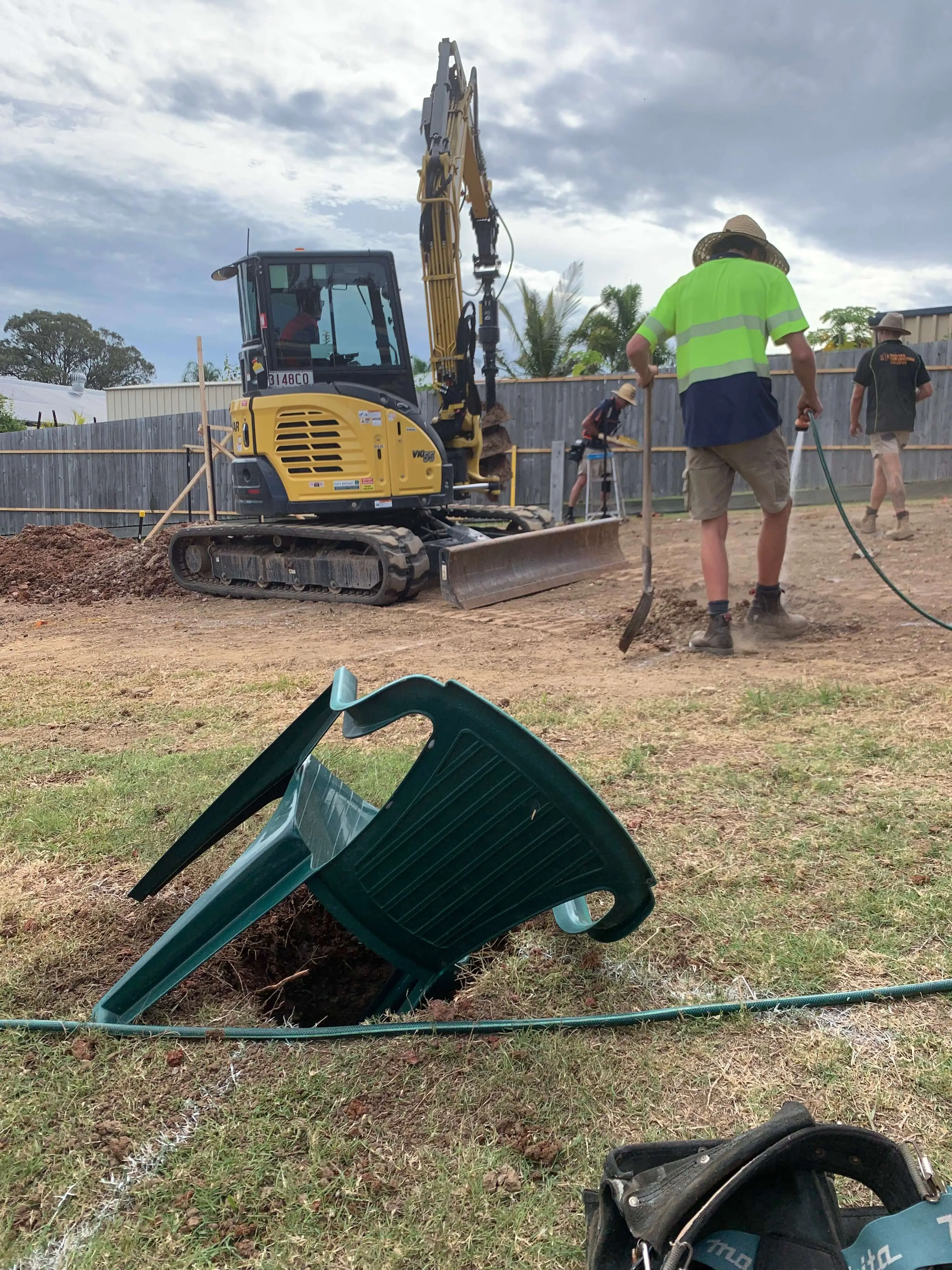 Excavator auger boring footing holes for structural posts