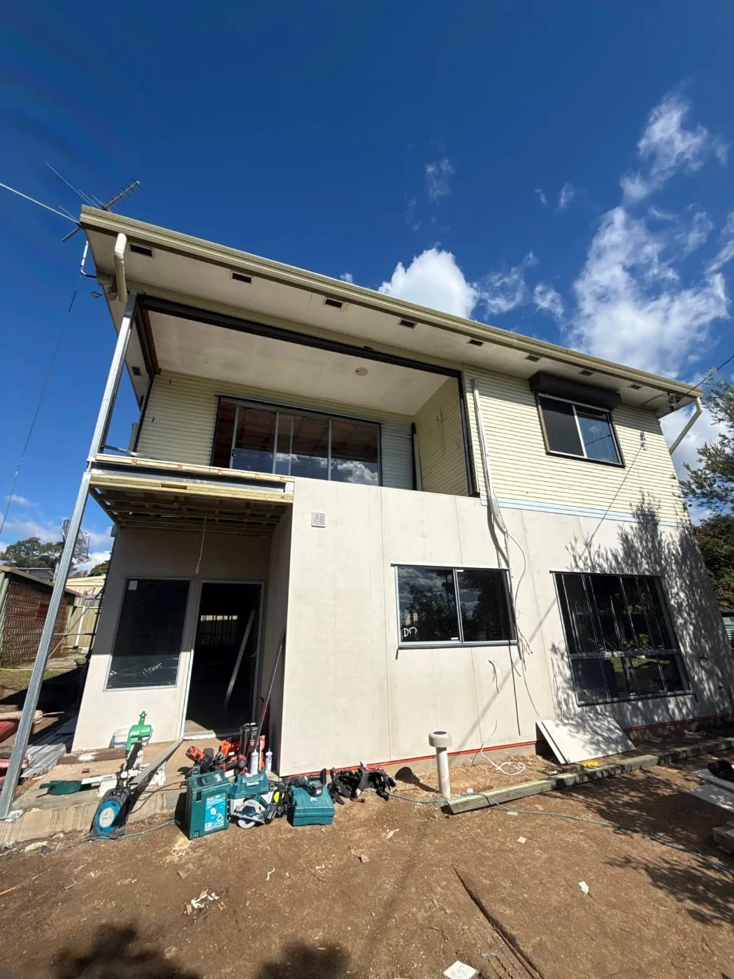 Rear of a Brisbane home mid-renovation with new two-storey extension cladding and windows