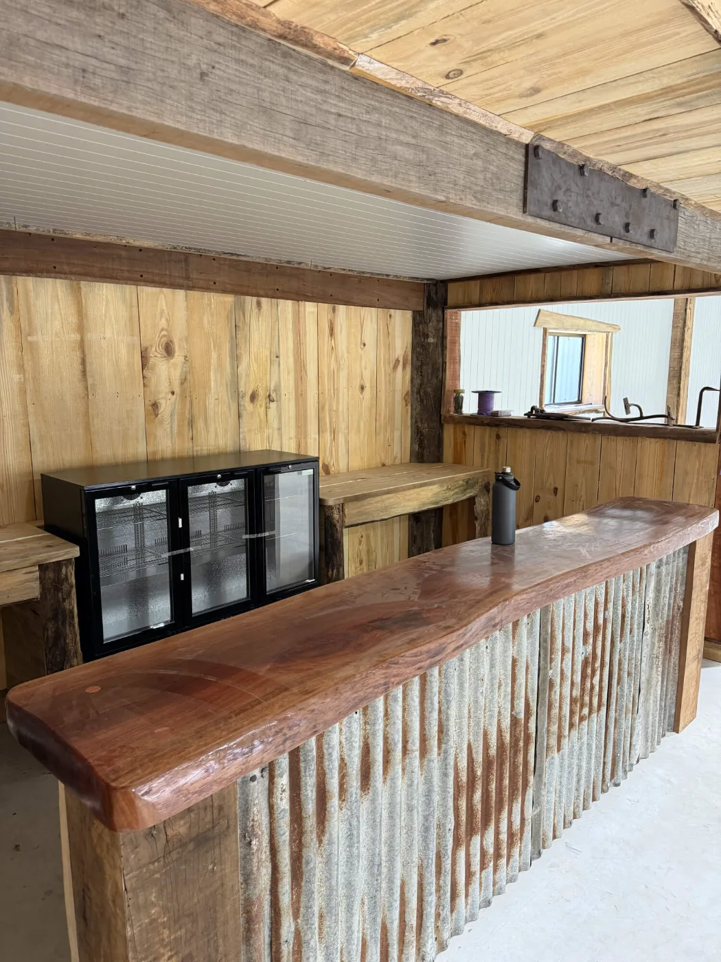 Polished hardwood slab bar top over corrugated iron cladding in a man cave