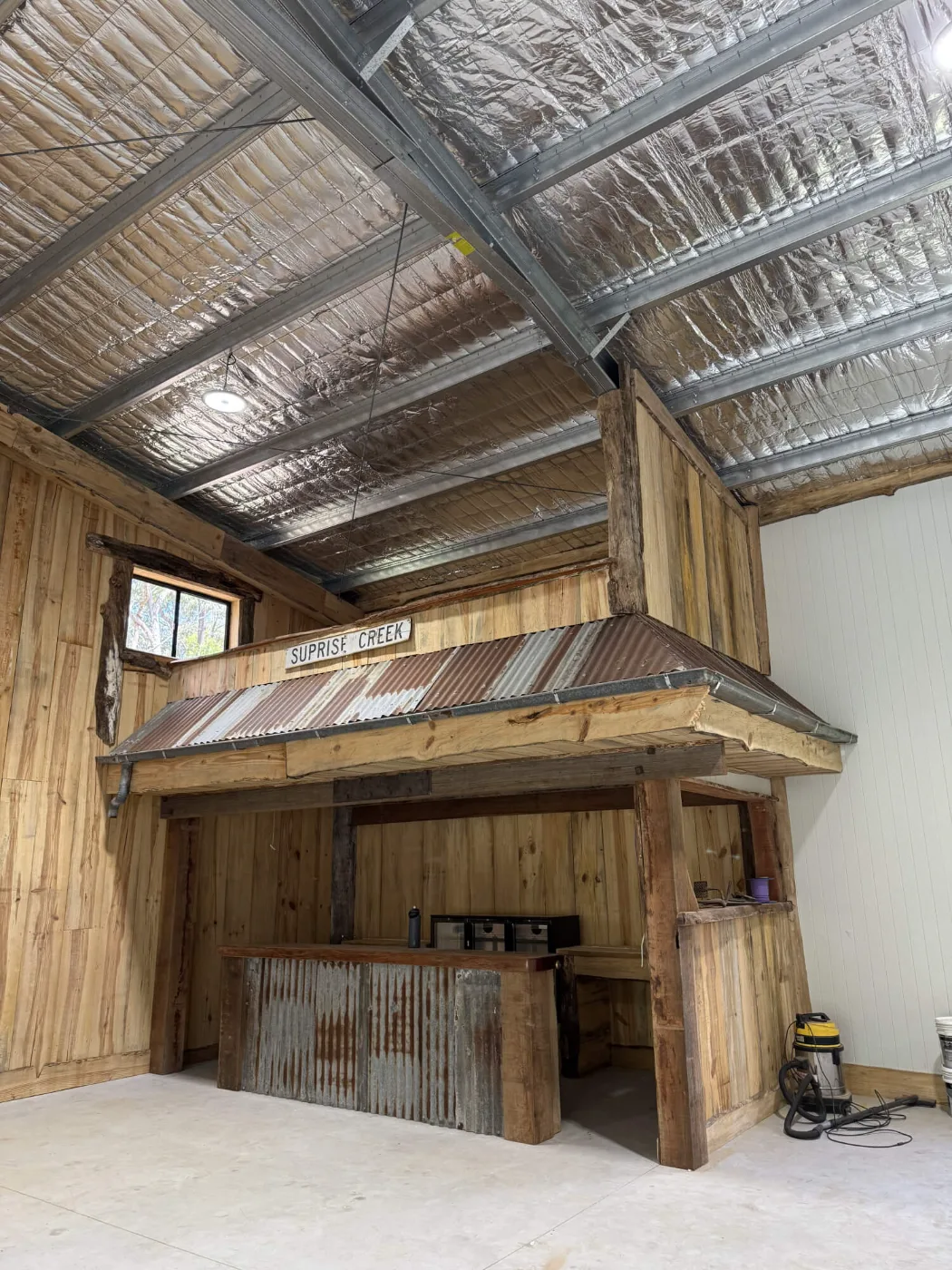 Custom bar clad in recycled corrugated iron with a timber awning inside a man cave