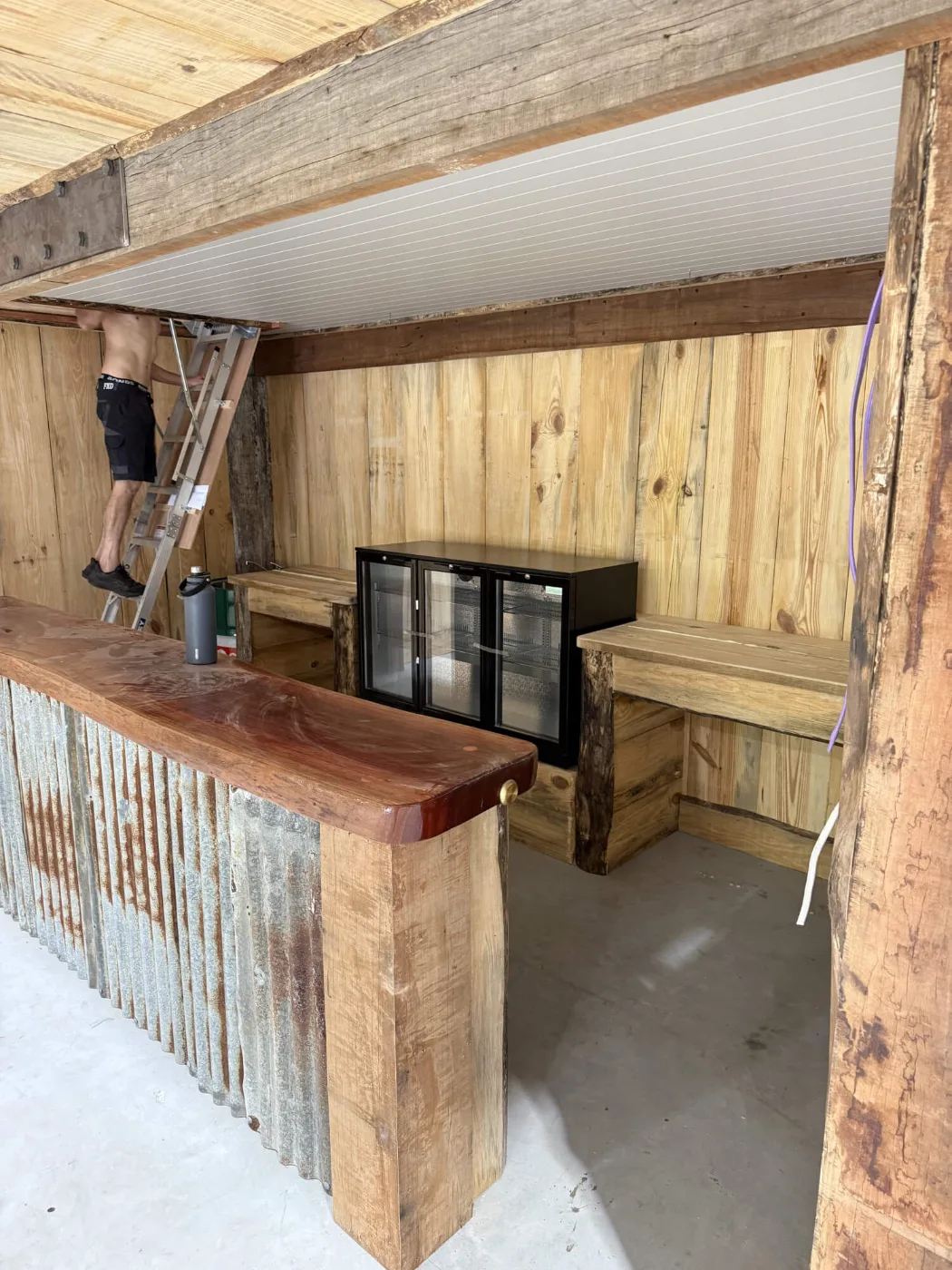 Timber bench seating and bar fridges built into a man cave bar nook